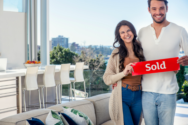 couple holding sold sign